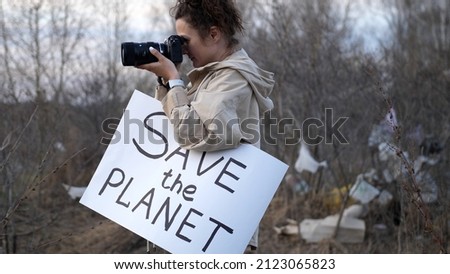 Ecology activist holding Save the Planet poster and looking at camera takes a picture protesting against littering planet, environmental pollution, save Earth