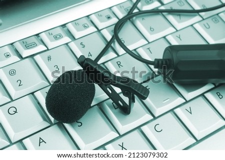 Lavalier microphone on laptop computer keyboard, broadcasting and streaming online concept