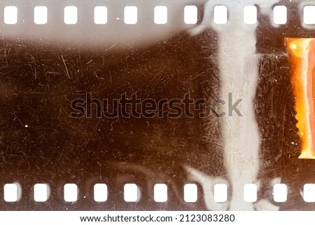 Dusty and grungy 35mm film texture or surface. Perforated scratched camera film isolated on white background. Royalty-Free Stock Photo #2123083280