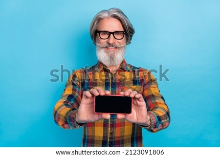 Photo of aged cheerful man demonstrate mobile promoter recommend sugest ad isolated over blue color background