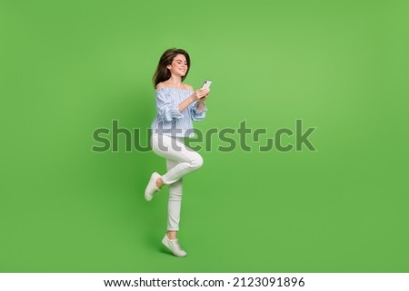 Full size photo of adorable young lady chatting with best friend use telephone isolated on green color background