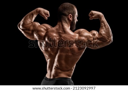 Muscular man showing back muscles, isolated on black background. Strong male rear view Royalty-Free Stock Photo #2123092997
