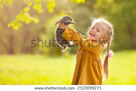 the girl is holding a little rabbit in her arms and laughing Royalty-Free Stock Photo #2123098271