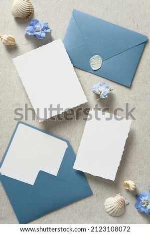 Nautical save the date cards mockups, blue envelopes, seashell on beige background. Wedding invitation card templates. Flat lay, top view, copy space.
