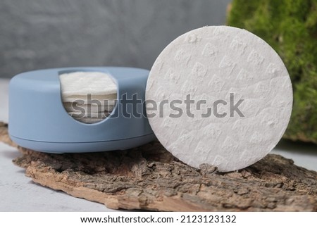 Reusable Cotton Rounds makeup remover in a container made from recycled ocean plastic on tree bark. Zero waste pads for to reduce environmental pollution.