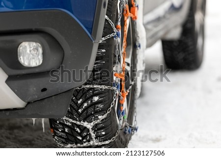 Picture of a vehicle tyre with snow chains on a frozen road 
