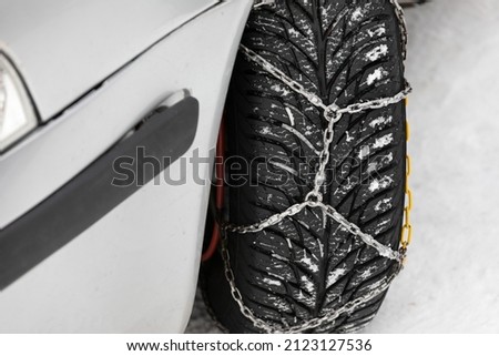 Picture of a vehicle tyre with snow chains on a frozen road 