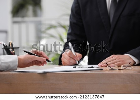 Woman reading document at table in office, closeup. Signing contract