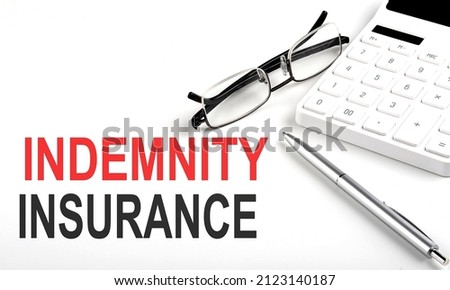 INDEMNITY INSURANCE Concept. Calculator,pen and glasses on the white background Royalty-Free Stock Photo #2123140187
