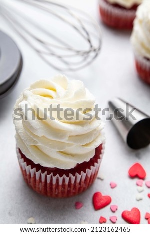 Red velvet cupcakes with cream cheese frosting on light background. Valentine's Day concept. Selective focus.