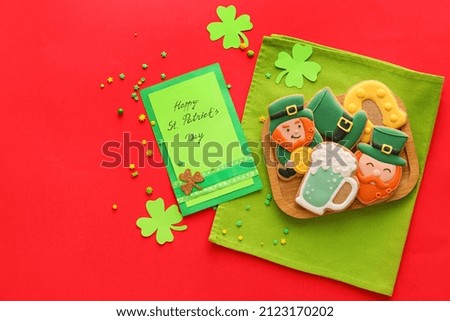 Composition with tasty gingerbread cookies for St. Patrick's Day celebration on red background