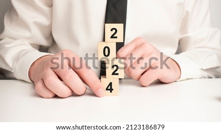 The word 2024. New year concept. Putting wood cubes with numbers and icons. Top view of wood table.