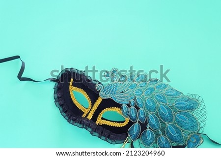Photo of black elegant peacock Venetian mask over blue background