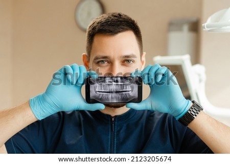 dentist holding a phone showing a panoramic x ray of the jaw