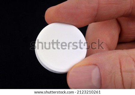 Effervescent aspirin pill held in hand close up on black background  Royalty-Free Stock Photo #2123210261