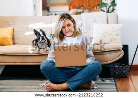 Freelancer businesswoman  working from home with a boston terrier dog. woman using laptop at sunny room. woman studying at home. Student learning and working at home.