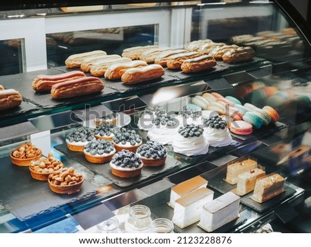 A lot of different desserts and sweets on display. Delicious pastries in the coffee shop. Variety of cakes, eclairs and cakes Royalty-Free Stock Photo #2123228876