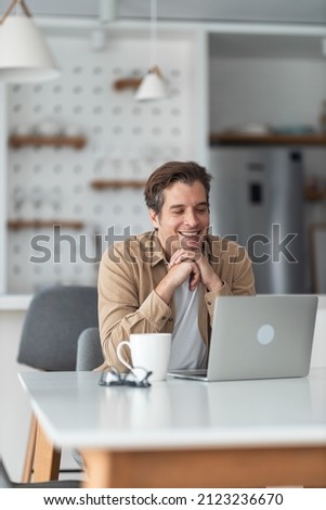Happy male freelancer reading an e-mail on laptop at home office. Royalty-Free Stock Photo #2123236670