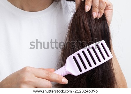 Girl combing tangled, brittle, split ends, care for long hair concept.