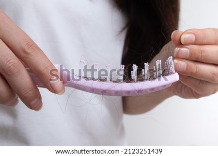 Comb in female hands with lost hair. Tangled and falling out hair, care for long hair concept.