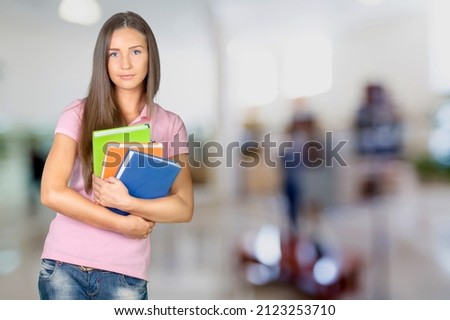 Portrait of a college student standing in a lecture room with books