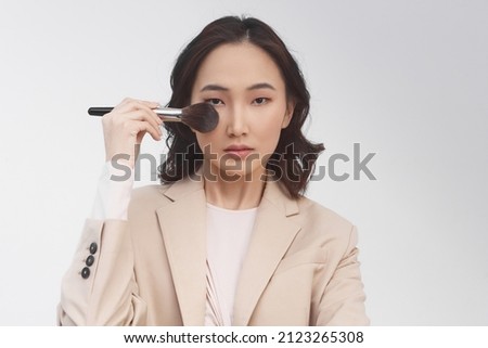 A horizontal photo, a pretty young asian girl holding brush for makeup. Beauty of women. Professional Makeup and Beauty, isolated on white background. Beauty concept. 