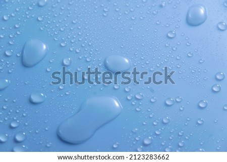 Blue pastel water drops on light shiny surface
