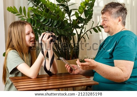 Senior Woman blogger talking with followers, live streaming, looking to smartphone screen. Social network,  embroider blogger concept. Teenage girl takes pictures, shoots video of her blogger grandma