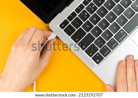 Woman plugging charger in a laptop. Type C charging port. Low battery concept
