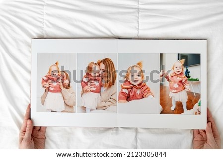 hands with Photobook of family at home on a white background. Photobook is gift. professional photographer and designer. printing of photos and journals in photo laboratory. mother and daughter