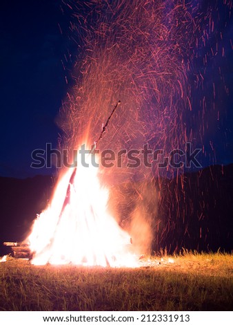 Large fire with sparks lit in the middle of the field at night