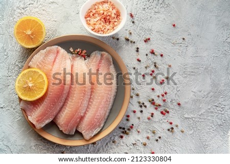 Tilapia fish fillet with spices and lemon. Healthy food rich in proteins. Royalty-Free Stock Photo #2123330804