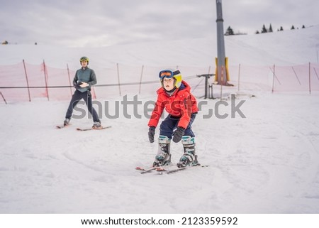 Boy learning to ski, training and listening to his ski instructor on the slope in winter Royalty-Free Stock Photo #2123359592
