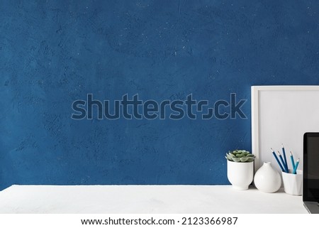 Home office desk with blue wall and white table mock up.	
