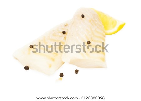 Cod fish raw pieces spiced with salt, peppercorns and lemon isolated on white background.