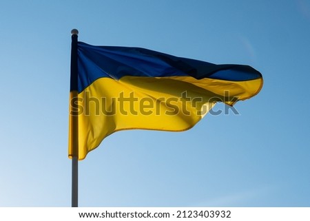 Ukrainian flag waving in wind and sunlight. Flag of Ukraine on blue sky background. National symbol of freedom and independence. Royalty-Free Stock Photo #2123403932
