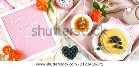 Pancake breakfast tray in bed with syrup and blueberries fruit creative layout flat lay top view, with letter felt board Happy Pancake Day message. Sized to fit popular social media and web banner.
