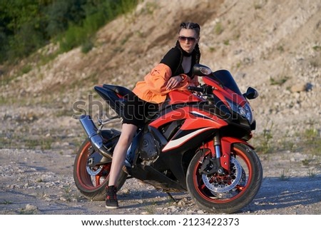 A girl on a motorcycle on the background of a hillside. Selective focus.                               