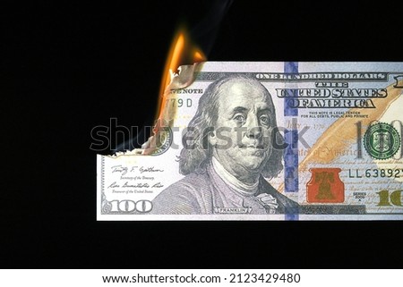Close up shot of a 100 dollar banknote burning on a black background. Royalty-Free Stock Photo #2123429480
