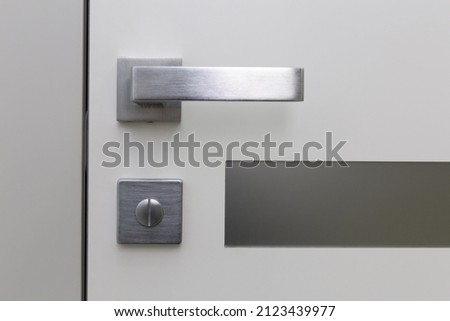 Metal handle with lock on plastic entrance door. Close-up photo of architecture detail. Interior fragment as geometrical conceptual background. Royalty-Free Stock Photo #2123439977