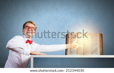 Young man in glasses pointing at opened book