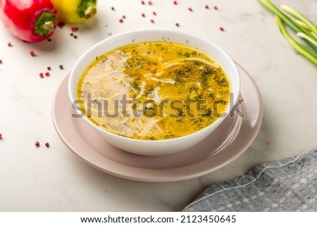 Chicken soup bouillon in a plate on white marble table