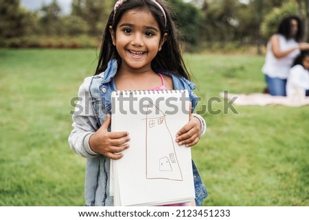 Portrait of indian female kid holding drawing book at city park - Focus on face