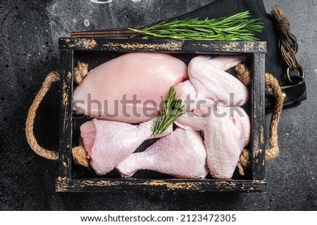 Fresh raw chicken meat and chicken parts - drumstick, breast fillet, wing, thigh. Black background. Top view Royalty-Free Stock Photo #2123472305