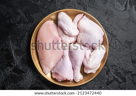 Fresh raw chicken meat with various parts - drumstick, breast fillet, wings, thigh. Black background. Top view Royalty-Free Stock Photo #2123472440