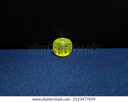Close-up of single yellow dice on blue background