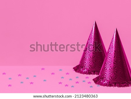 Pink party hats. Photo with copy space. Two shining cones and colorful confetti on pink backdrop