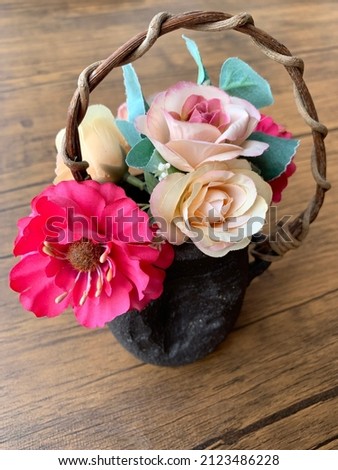 Colorful artificial fabric flowers in black pottery vase with rattan handle Royalty-Free Stock Photo #2123486228