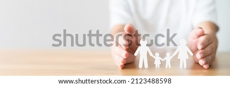 Hand protecting family on wood table. Healthcare and life insurance concept Royalty-Free Stock Photo #2123488598