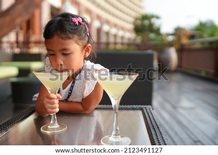 Cute little girl drinking welcome drink at table. 